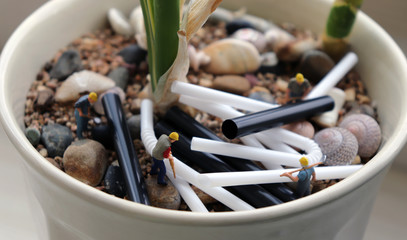 Miniature workers with disposable plastic straws. Concepts on plastic product processing issues.