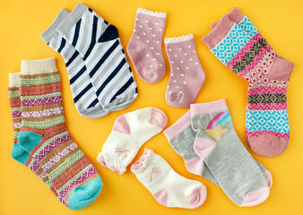 Socks on a yellow background. View from above. Socks of different sizes and colors on a bright yellow background. Clothing in the form of socks for adults and children.