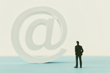 miniature man looking at arroba or at sign