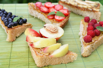 different delicious toasts on green or pink crimson background. Healthy sandwich for breakfast or snack. Toast with raspberries, strawberries, banana and blueberries and peanut butter. picnic concept