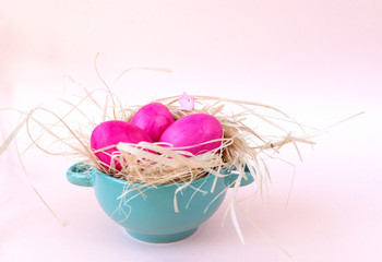 3 pink eggs, Easter, hay, green plate, beige background,