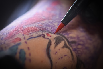 Female tattoo artist making tattoo on a men’s arm