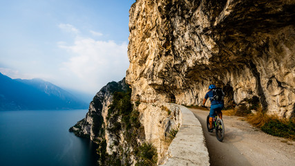 Cycling man riding on bike at sunrise mountains and Garda lake landscape. Cycling MTB enduro flow...