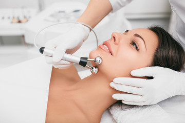 Beautiful woman receiving facial microcurrent procedure for lifting face. Facial rejuvenation and...