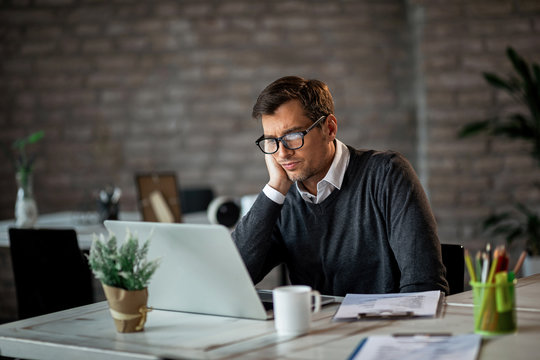 Displeased businessman reading something on laptop while working in the office.
