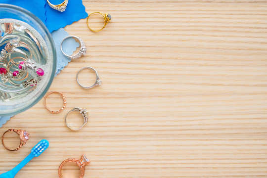 Cleaning Jewelry Diamond Ring With Glass Of Hot Water And Dishwashing Liquid On Wood Table Background