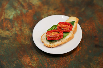 tomato basil bruschetta starter on a white plate with rustic background