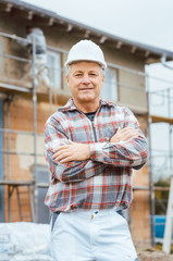 Proud plasterer standing in front of scaffold on construction site