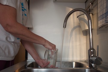 Woman washing dirty glass in the sink