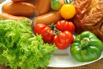 fresh vegetables,  sausage and cooked chicken on a plate. 