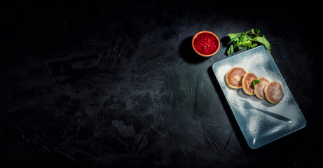 Cottage cheese pancakes sprinkled with powdered sugar on a dark background. Healthy food for breakfast