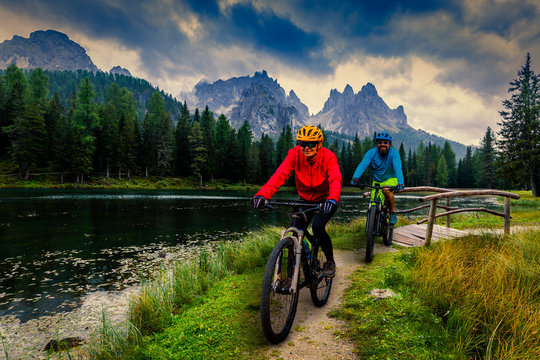 Cycling woman and man riding on bikes in Dolomites mountains andscape. Couple cycling MTB enduro trail track. Outdoor sport activity. © Gorilla
