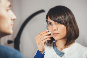 Doctor ophthalmologist holding lenses to check  patient's vision.  focus on  lens,  face is in soft...