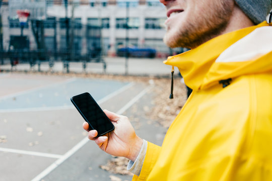 Man in yellow raincoat standing on the street with mobile phone in hand