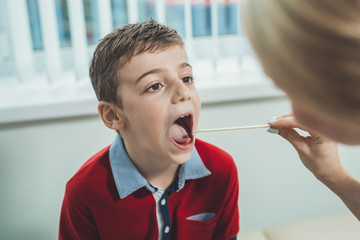 boy has strep throat. Children's ENT doctor examines  boy's throat. Children's diseases, medical...