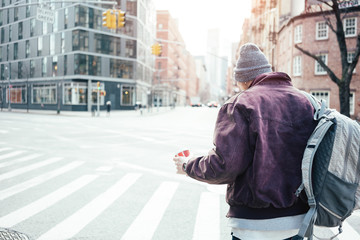 Man with cup of coffe crossing street in the city