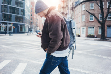 Smiling man with mobile phone crossing street in the city