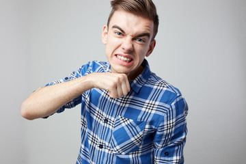 Aggressive  guy dressed in a plaid shirt is on a white background in the studio