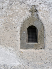 Fototapeta premium Old stone window with fleur de lys religious motif and grille.