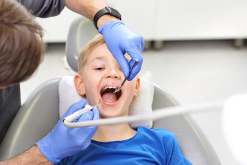 Dziecko u stomatologa .Leczenie zęba, stomatolog czyści ubytek