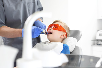 Dziecko na fotelu stomatologicznym podczas zabiegu leczenia zębów - obrazy, fototapety, plakaty