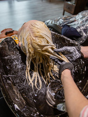 Hairdresser washing hair for a blonde girl.