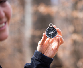 Compass holding in the hand of a girl, outdoor adventure, blurry face