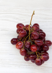 Bunch of ripe red grape on a white wooden table, top view. Close-up.