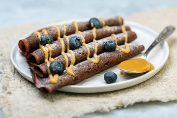 Chocolate crepes with caramel and powdered sugar.