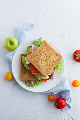 Overhead shot of a healthy sandwich with greens, ham, tomatoes and cheese. Lunch ideas for school or for work