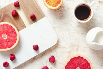 Breakfast table with fresh coffee, grapefruit, oranges and raspberries.
