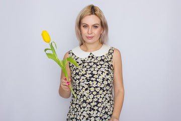 Blonde woman holding one yellow tulip