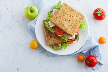 Overhead shot of a healthy sandwich with greens, ham, tomatoes and cheese. Lunch ideas for school...