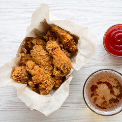 Freshly fried chicken wings with ketchup, cold beer, overhead view. From above, close-up.