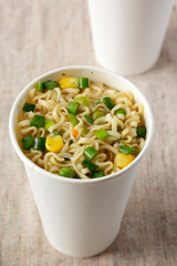 Tasty instant noodles with beef flavoring in paper cups, side view. Close-up.