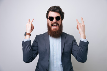 Businessman shout and showing rock and roll sign. Business people concept, richly and success. Indoor, studio shot on light gray background