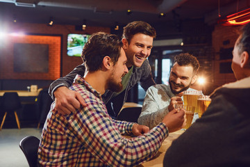 Friends talk, drink beer in a bar.
