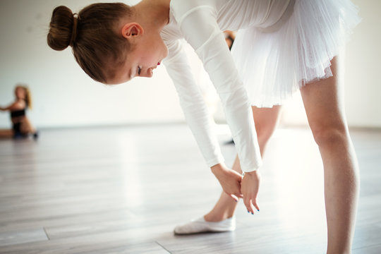 Young ballerina in tutu practicing dance moves. Young girl in ballet dress in dance school.