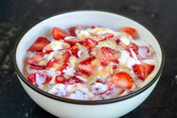 Red strawberry and white yogurt brulee. Fruit dessert on breakfast with wedges of perfectly ripe in season strawberry, closeup