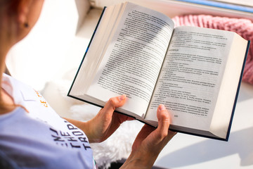 Yong woman holding a book in her hands.