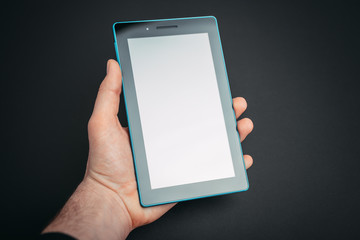 Photo of man hand holding a tablet on dark gray isolated background