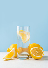 Detox lemon water with lemons fruit half and full on blue background