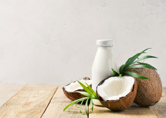 Obraz na płótnie Canvas Coconut milk in glass bottle with coconuts on white