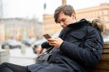 person use phone in the street and sit on bench b