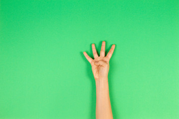 Kid hand showing four fingers on green background