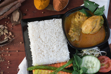 top view of chicken curry with vegetable, herb and spices on a wooden table and white napkin