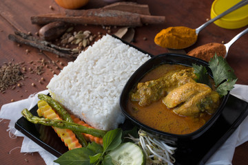 the chicken curry with vegetable, herb and spices on a wooden table and white napkin