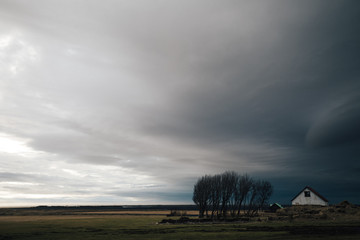 house in a field with oncoming weather storm on the horizon
