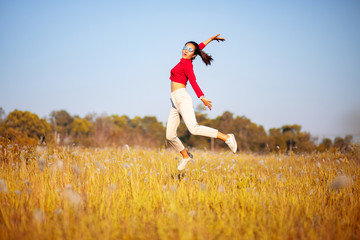 Fototapeta premium Happy Asian girl jumping in the grass field