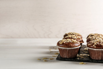 Slate plate with tasty almond muffins on white table
